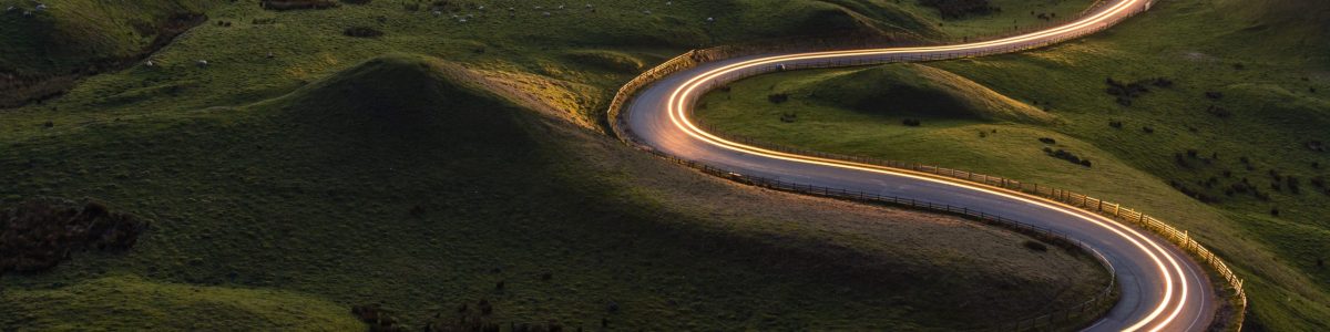 Winding curvy rural road with light trail from headlights leadin